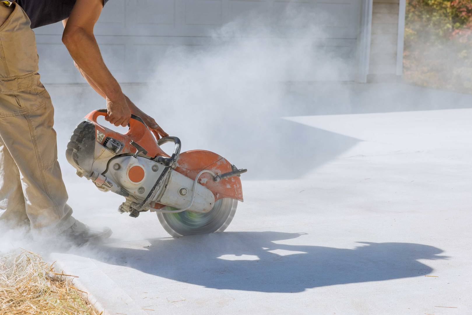 Construction worker cuts with working diamond bladed cut off saw to concrete paving sidewalk