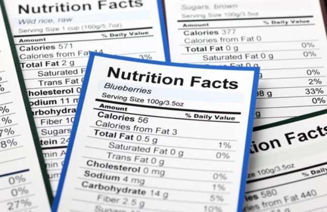 Farklı yiyeceklere ait birden fazla besin değeri etiketinin yakın plan görüntüsü; odakta yaban mersini etiketi yer alıyor.