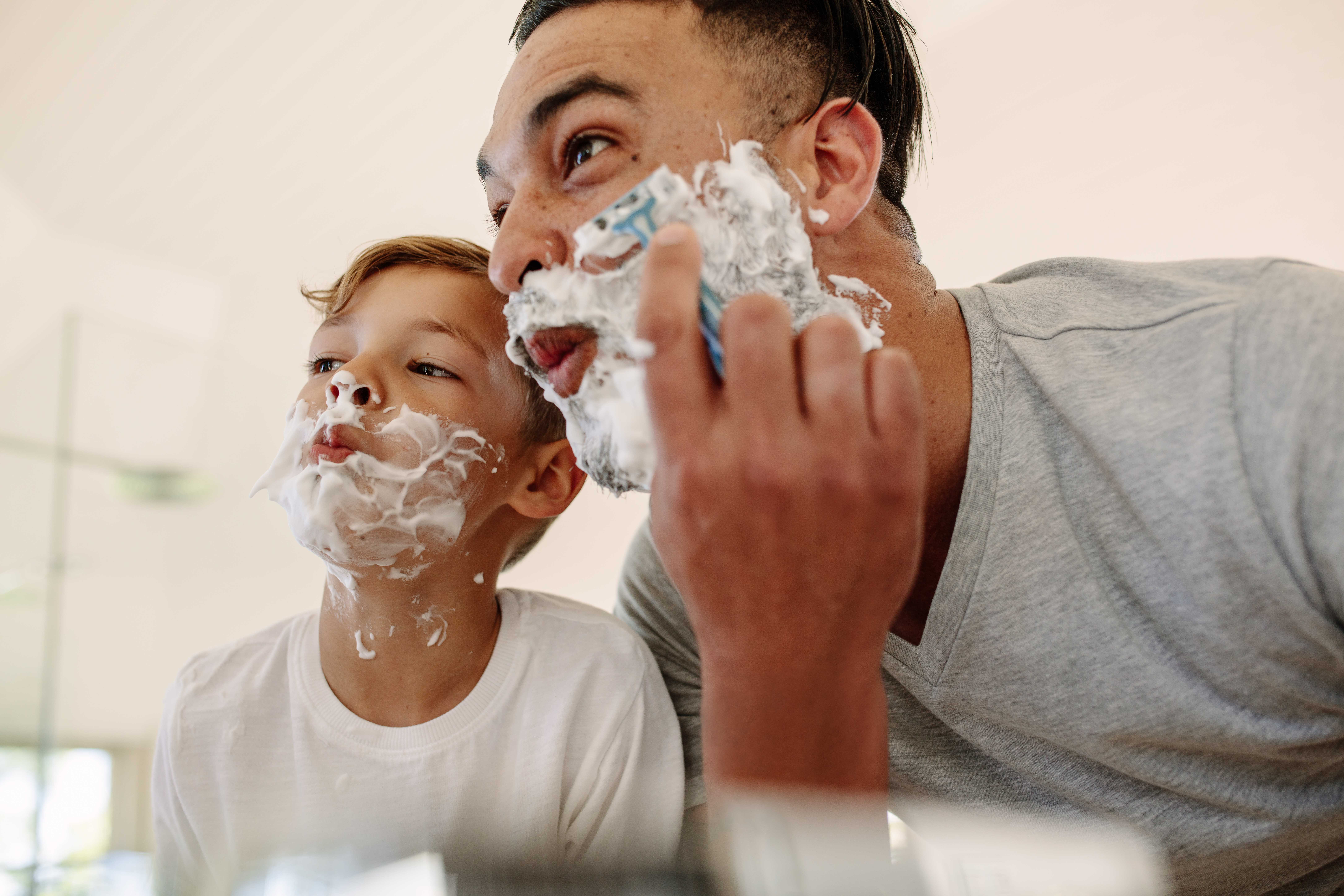 Funny father and son shaving in bathroom