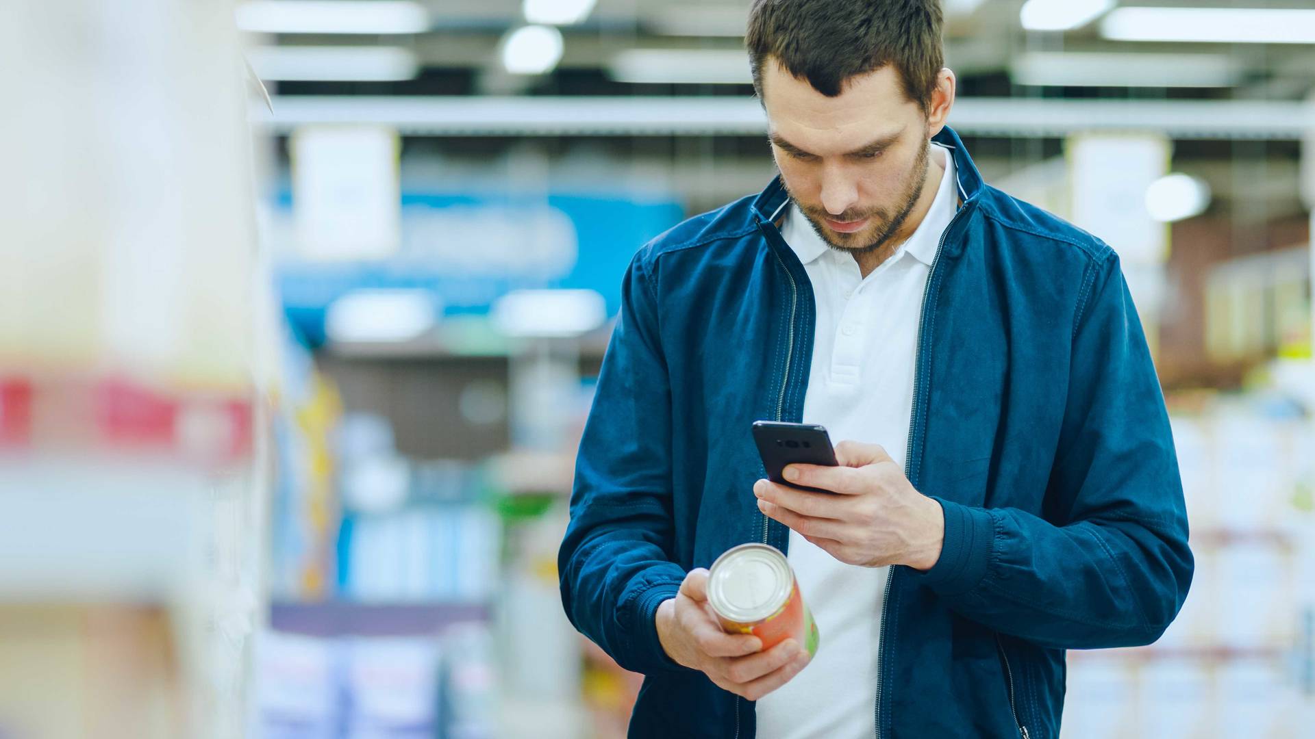 Casually dressed male scanning the nutritional label in a supermarket