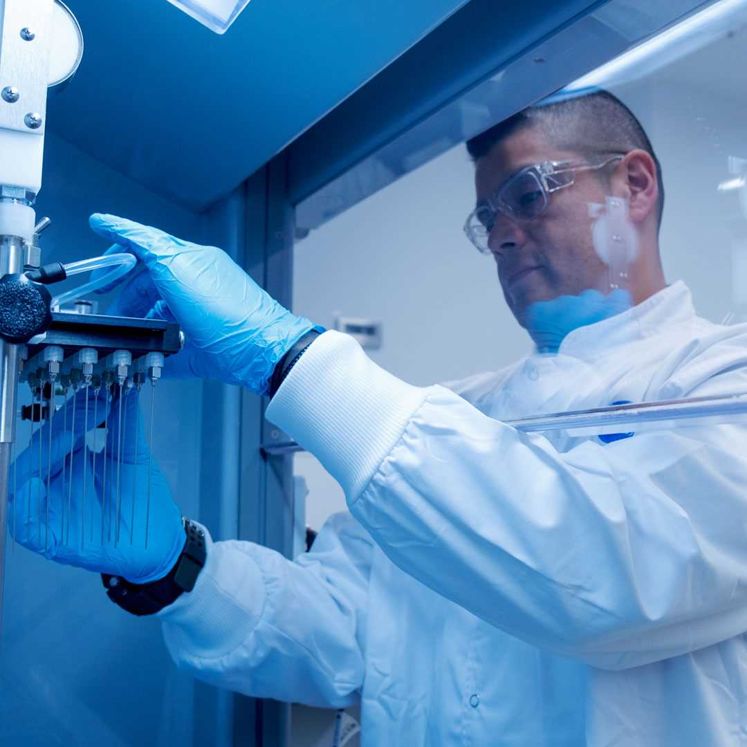 Lac technician adjusting apparatus in fume cupboard