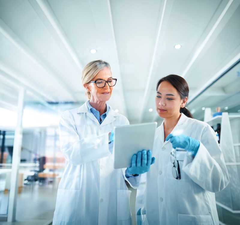 Scientists review research results on a tablet in a laboratory.