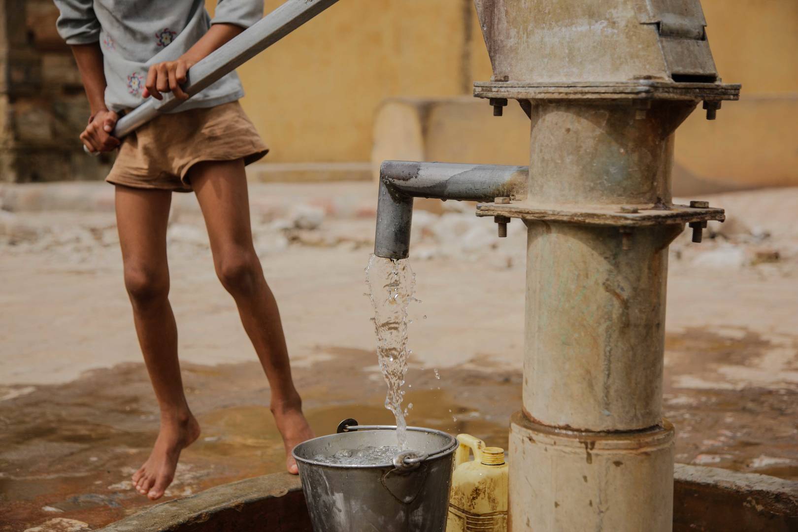 boy pumping water well