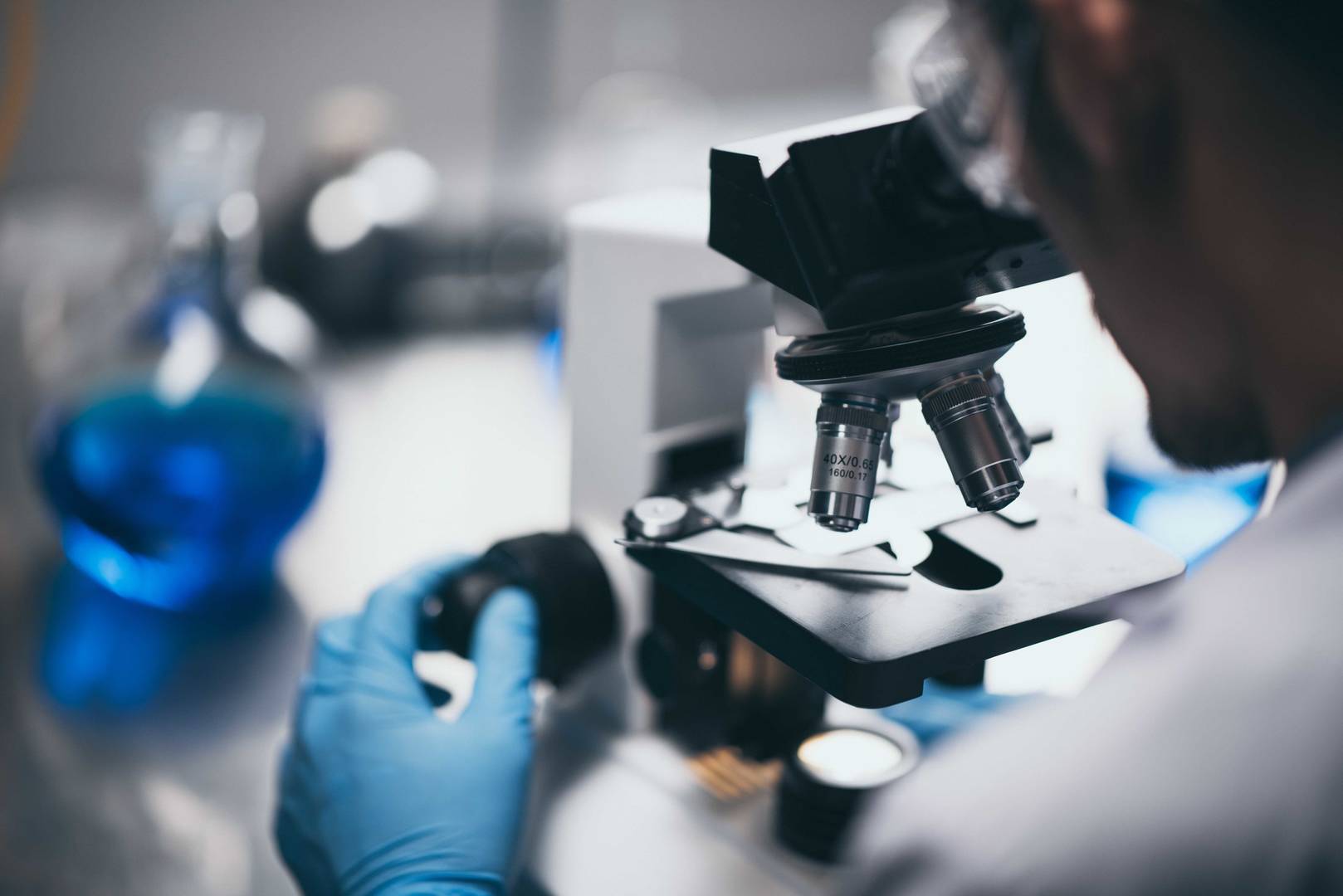 Mladý vědec se dívá do mikroskopu v laboratoři. Mladý vědec provádějící výzkum.