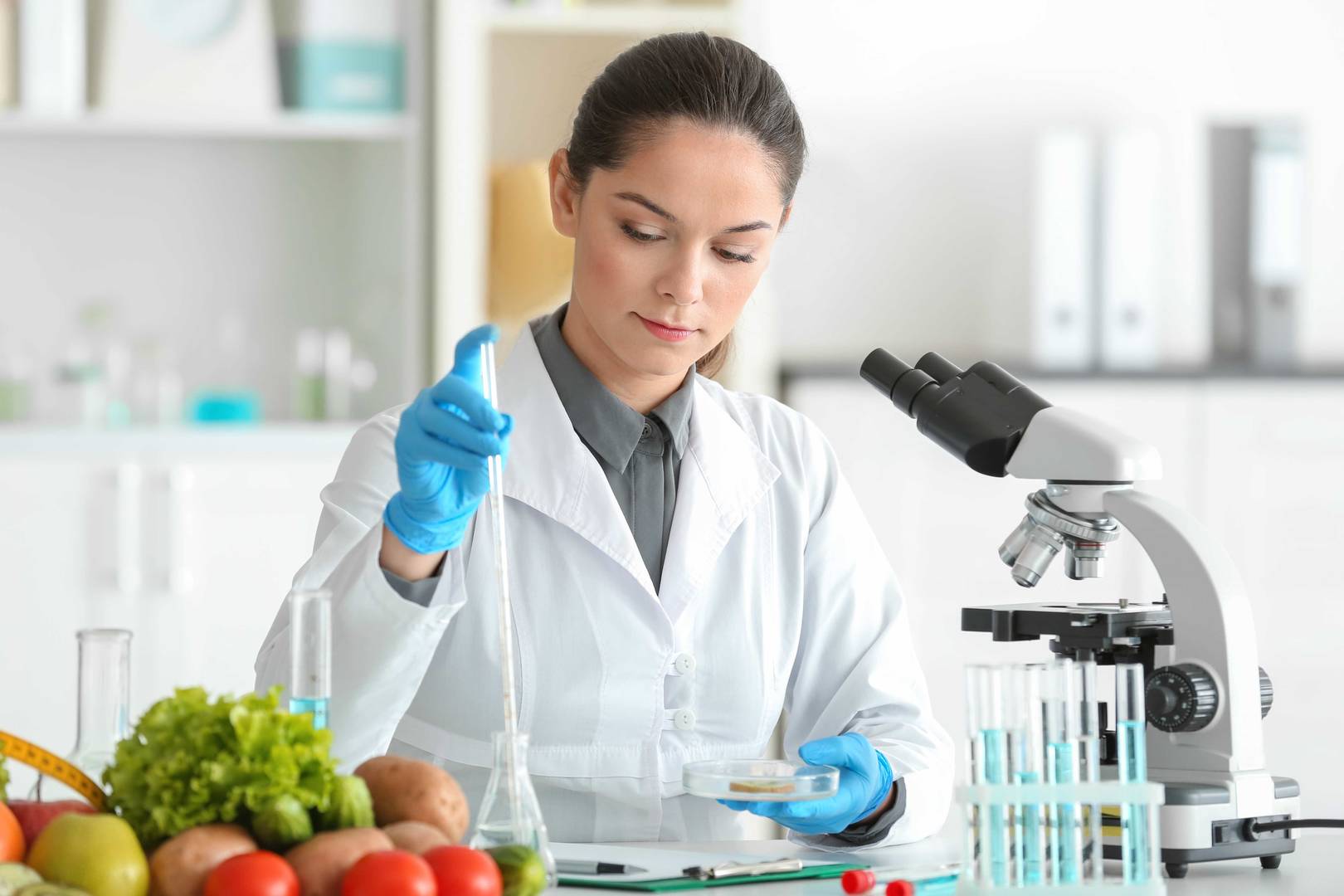 Mladá nutriční specialistka testující vzorky potravin v laboratoři.
