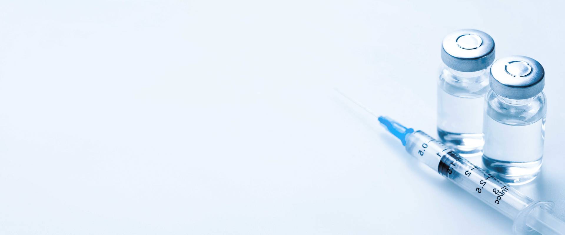 Spruta och två glasflaskor med vaccinliknande vätska på ljus bakgrund.