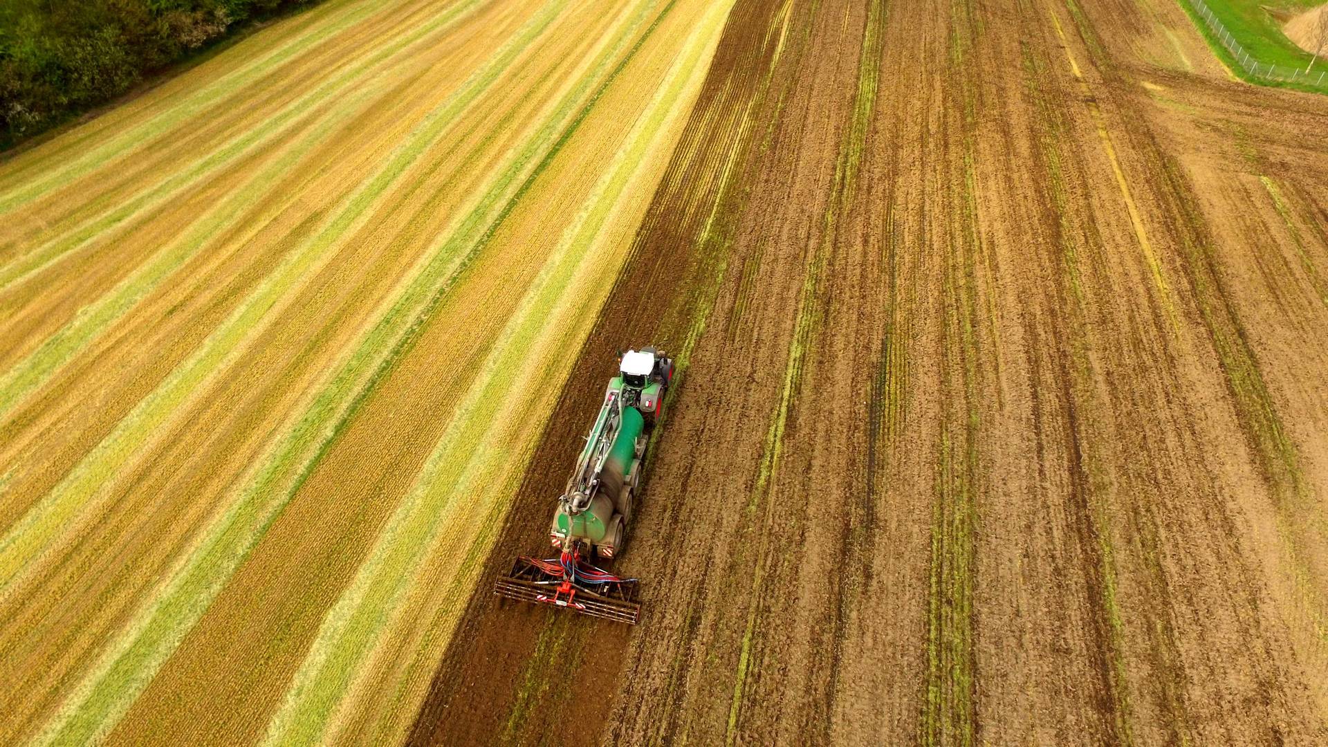 Ackerbau und Landwirtschaft. Ein Trecker verteilt Dünger auf dem Feld 