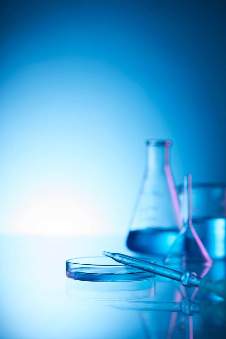 Mehrere Labor-Glasgefäße vor blauem Hintergrund als symbolische Darstellung für Laborarbeit und wissenschaftliche Forschung.