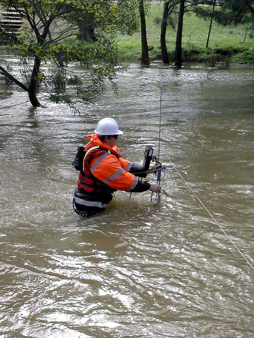 Hydrographics worker standing in flowing water while attending to measurement equipment