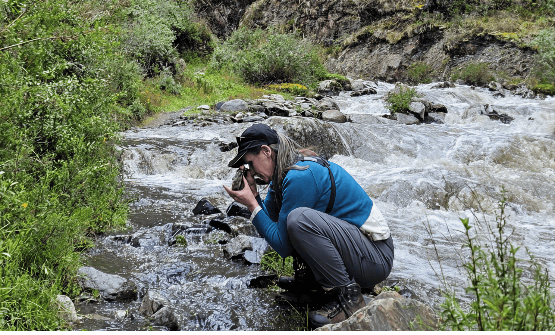 women taking pictures of rock samples by the river side